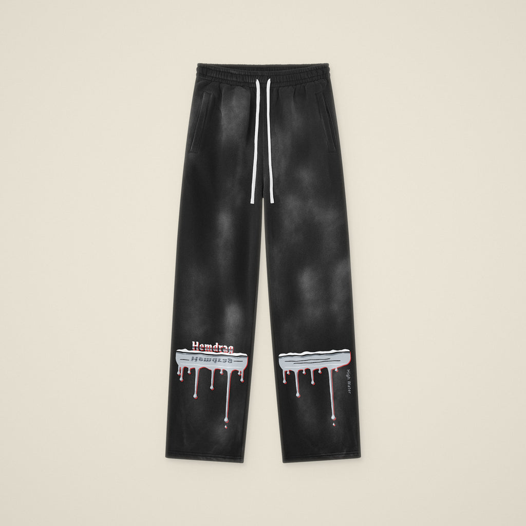 Digital preview: the High Water sweatpants laid flat, front view, with the chrome flood line and drips across both lower legs. The print was added digitally to a photo of the blank pants.